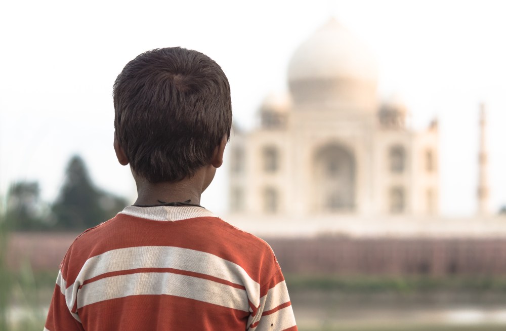 A young cowherd stares at the Taj Mahal, lost temporarily in thought.